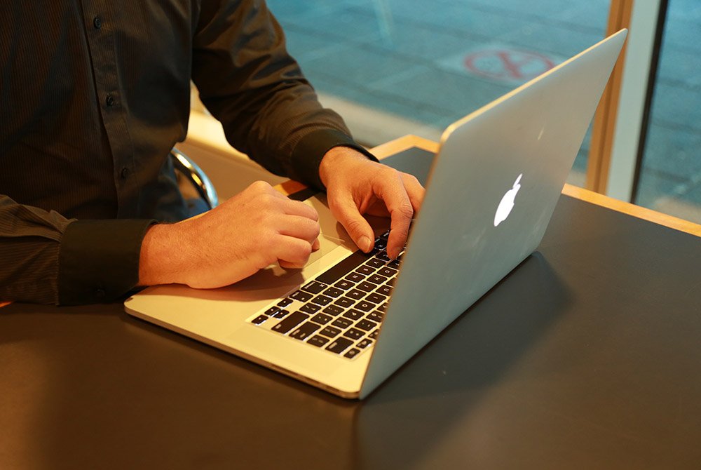 Person with apple laptop sitting at a desk
